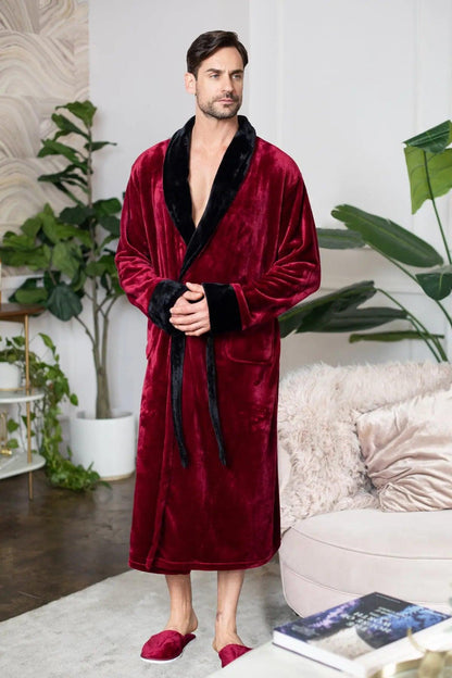 Man wearing a red velvet robe with black trim in a living room setting.