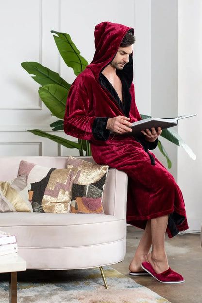 Person wearing a red velvet robe sitting on a couch holding a book.