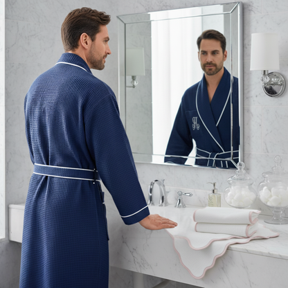 Man in a blue robe standing in front of a bathroom mirror.